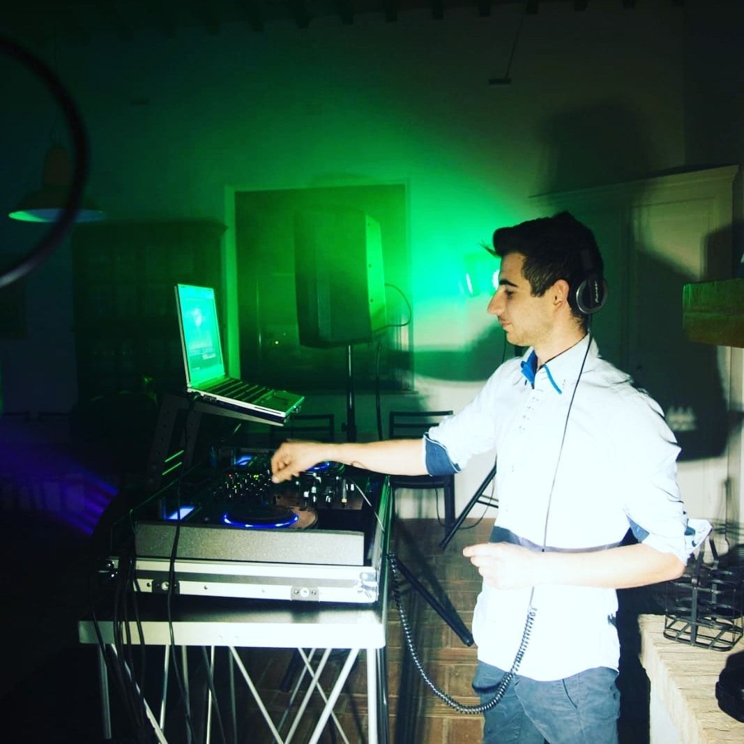 Dj Lator con le cuffie in una stanza buia illuminata da luci verdi