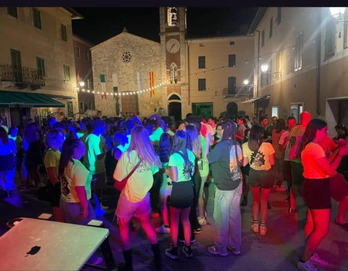 Un folto gruppo di persone balla davanti a una chiesa di notte.