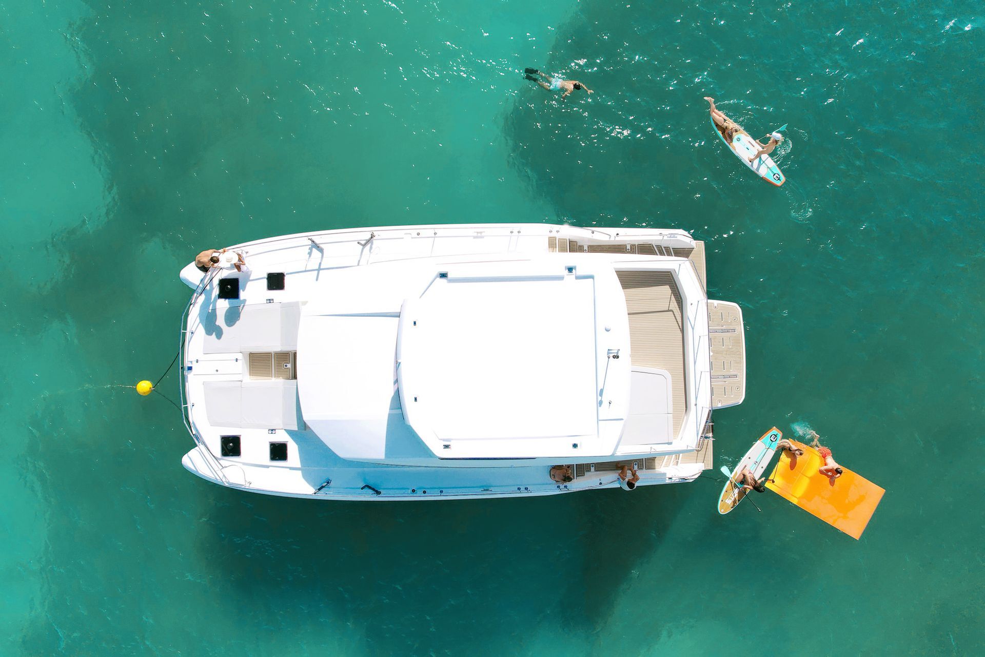 Aerial drone view on top of the Leopard 53 Power Catamaran by Arawak Charters in the crystal sea water with guests enjoying.