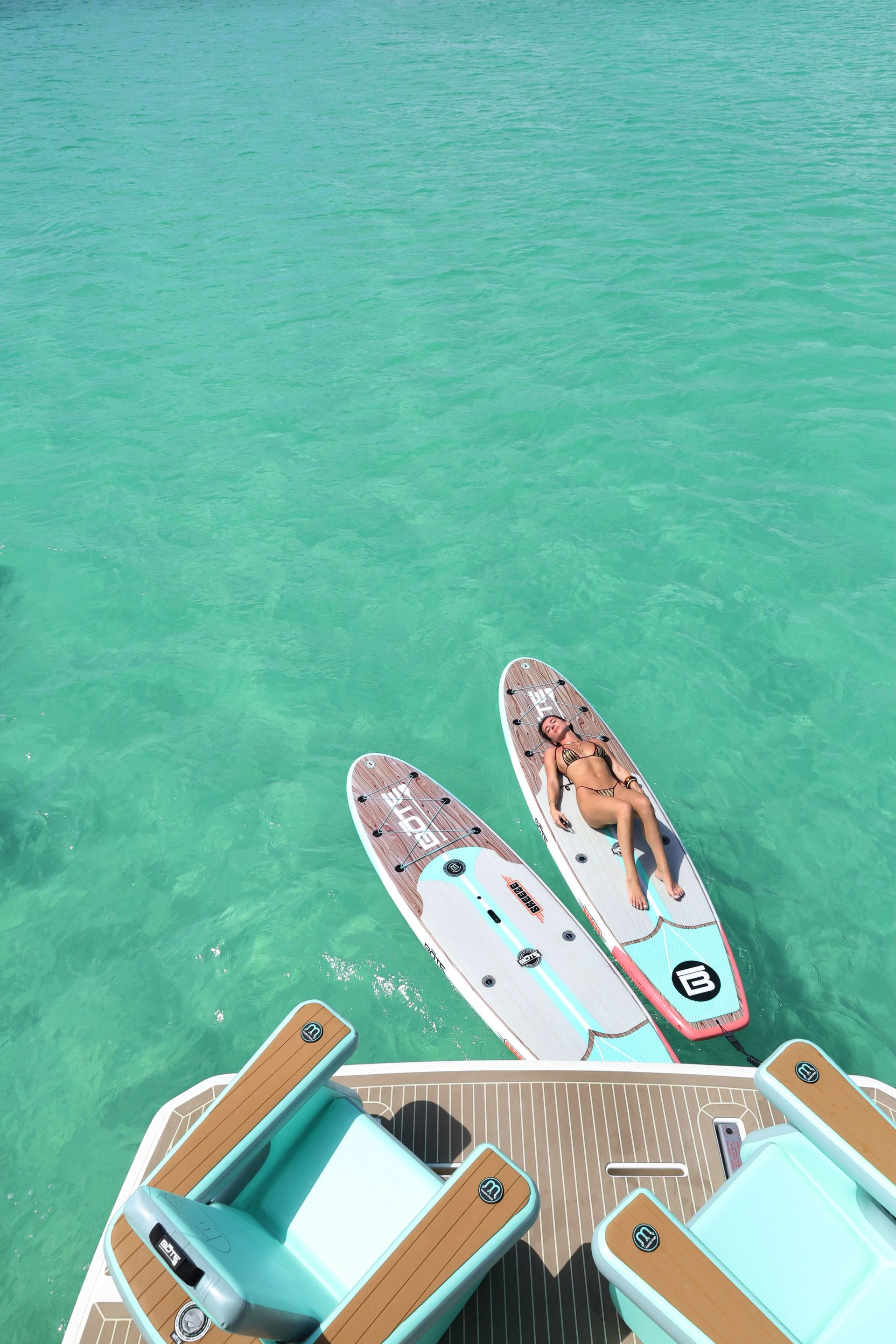 Guest relaxing on paddleboard, with Arawak Charters, in crystal-sea water, Anguilla
