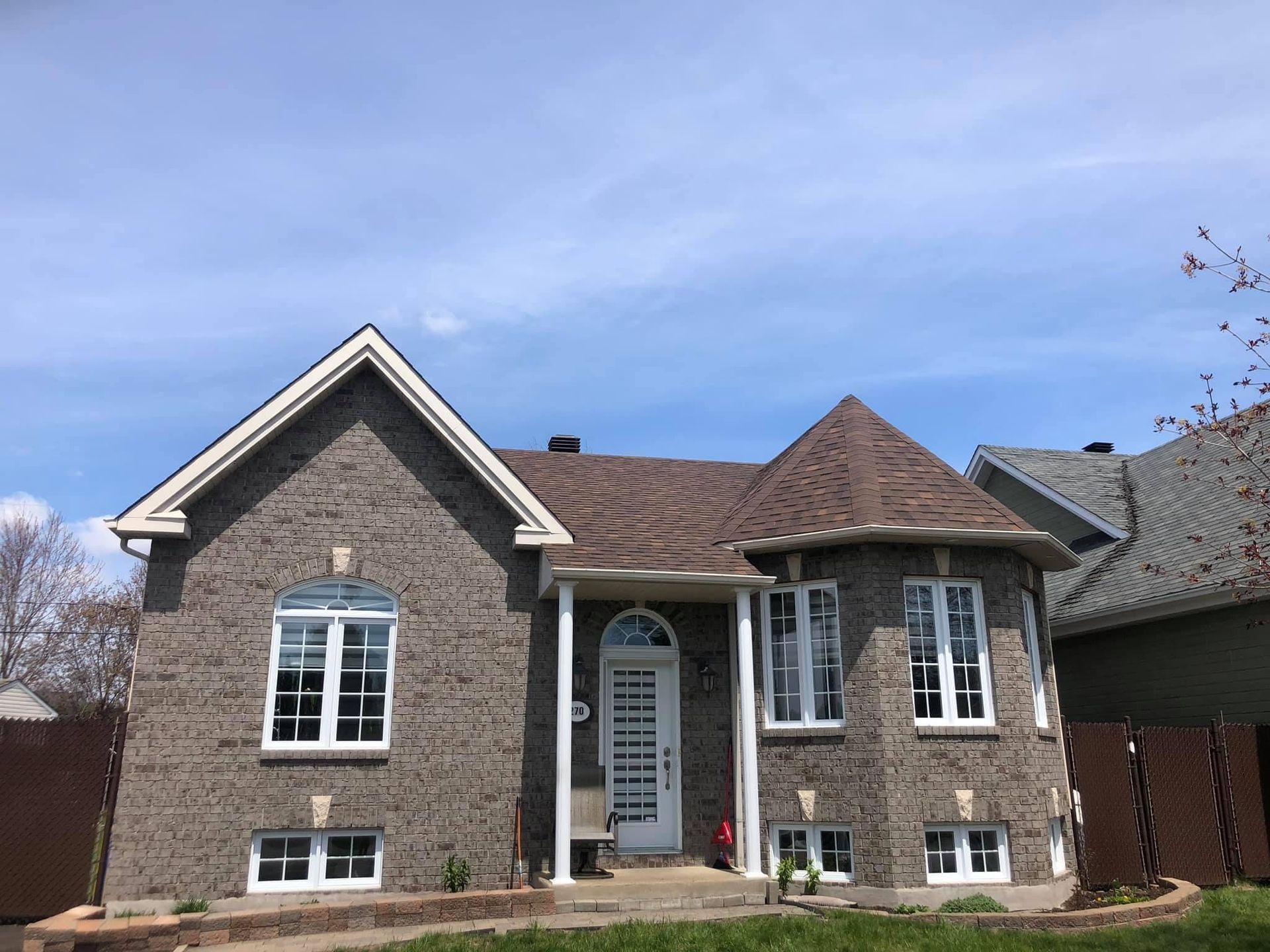 Une grande maison en briques avec un toit brun et des fenêtres blanches.