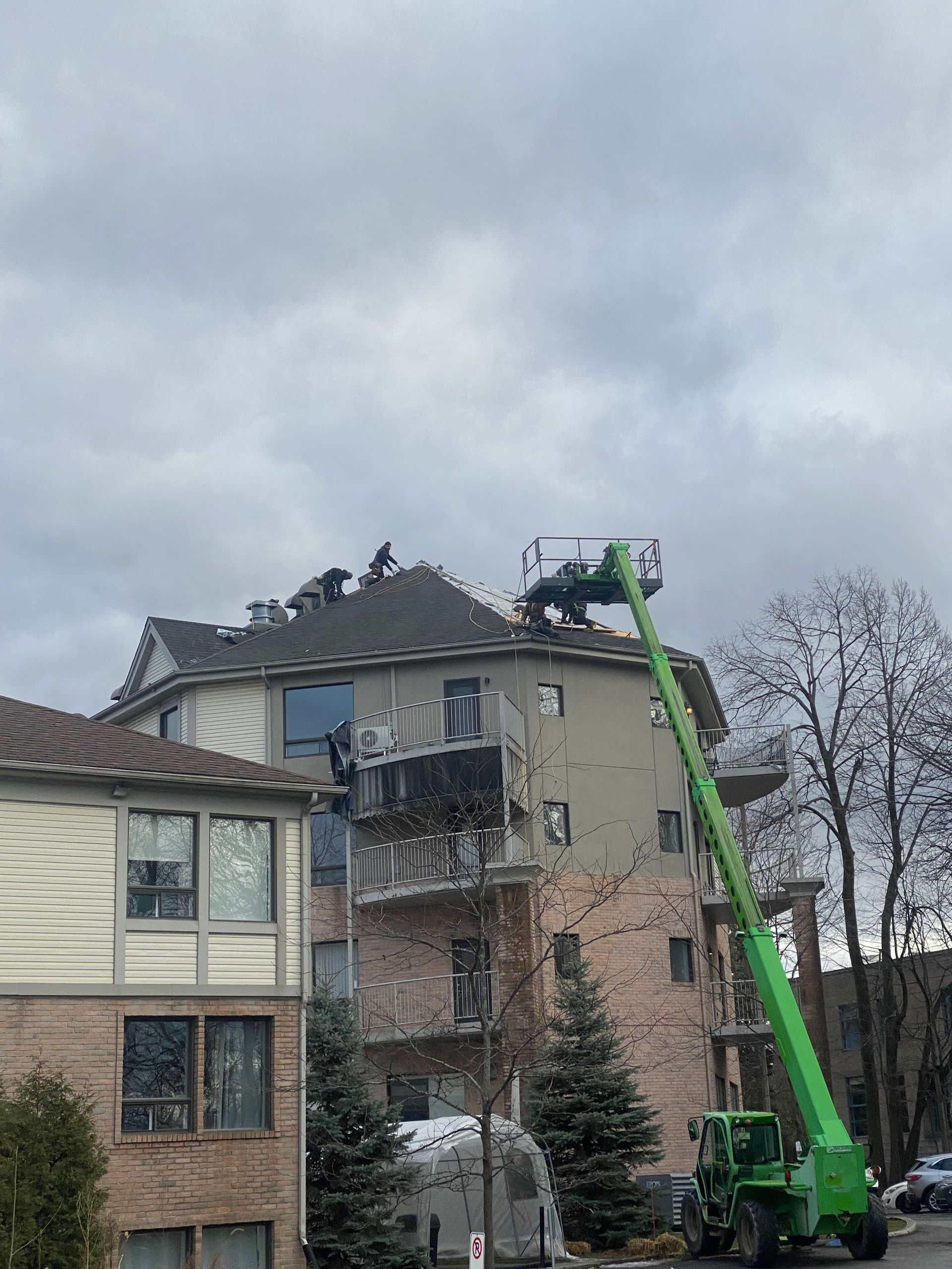 Une grue verte travaille sur le toit d'un bâtiment.