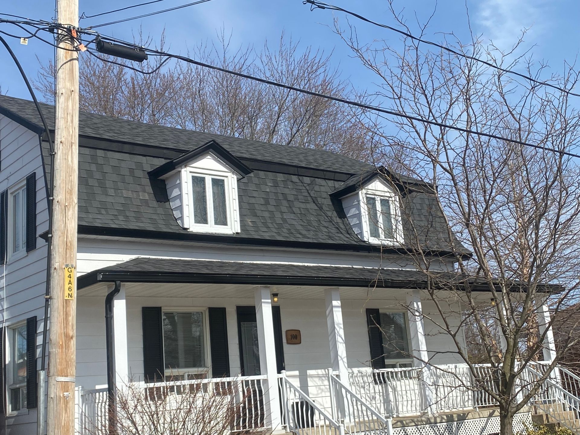 Une maison blanche avec un toit noir et des volets noirs