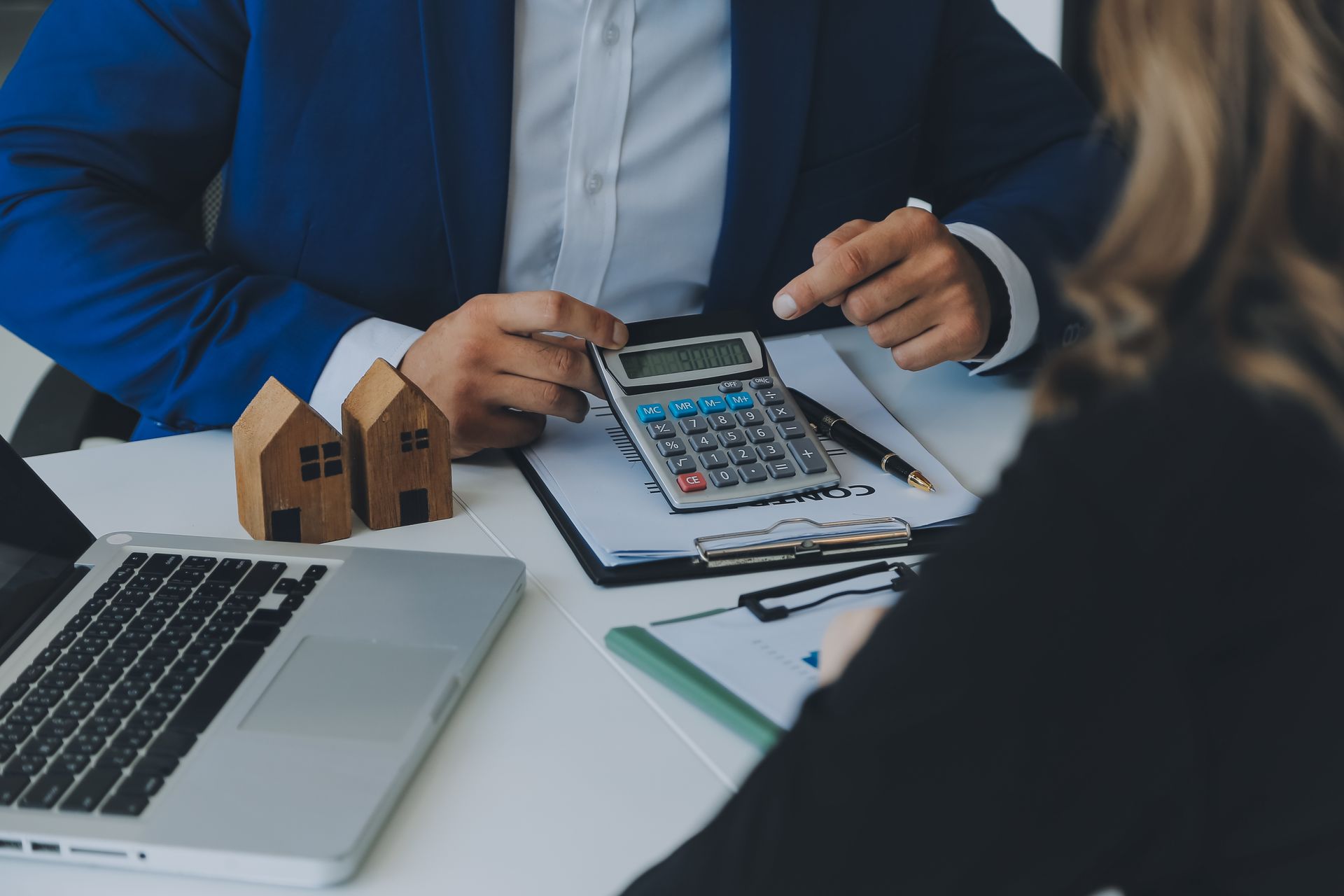 A man and a woman are sitting at a table using a calculator.