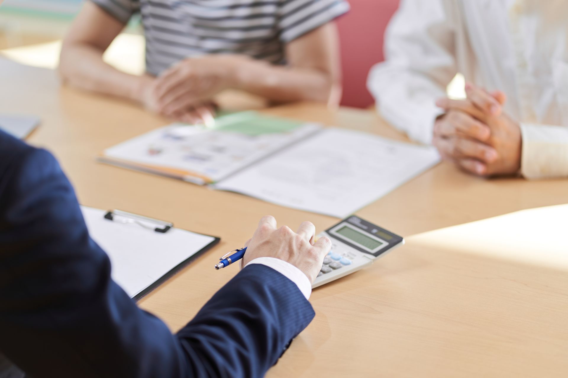 A group of people are sitting at a table with papers and a calculator.