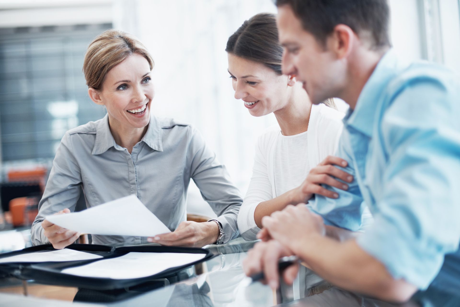 Consultant in an insurance agency explaining a document to a young couple.