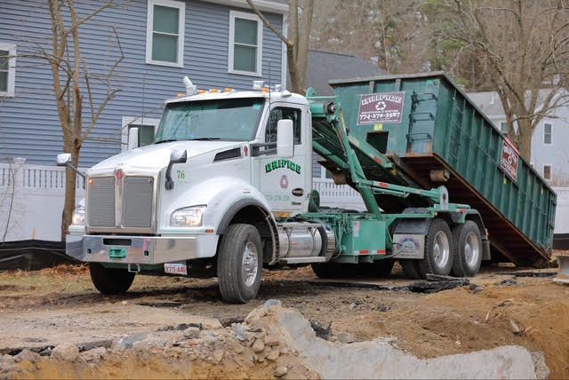 White Orifice dump truck with green container on a construction site.