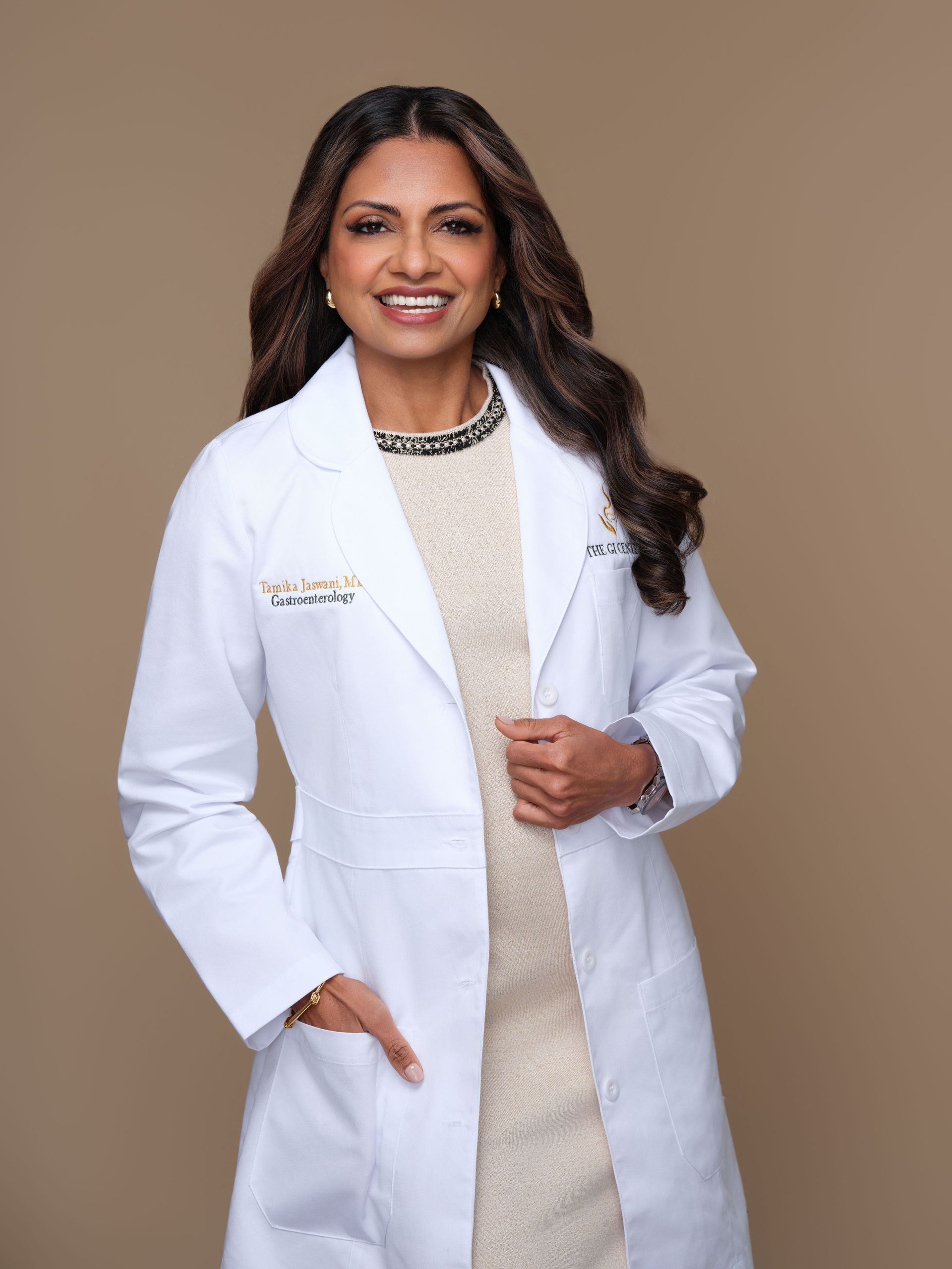 Doctor in a white coat, smiling, beige background, hand in pocket.