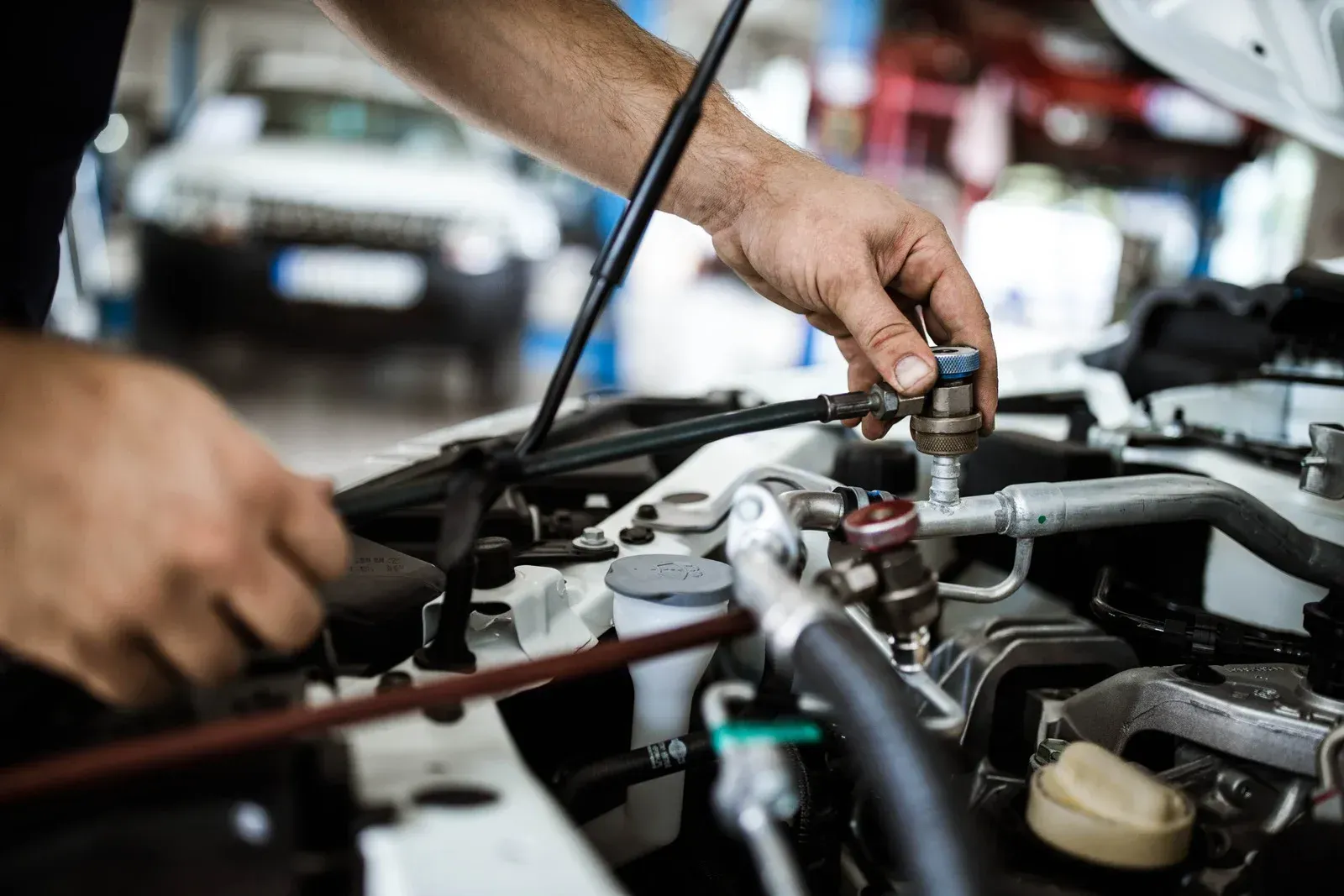 A man is working on the engine of a car in a garage.