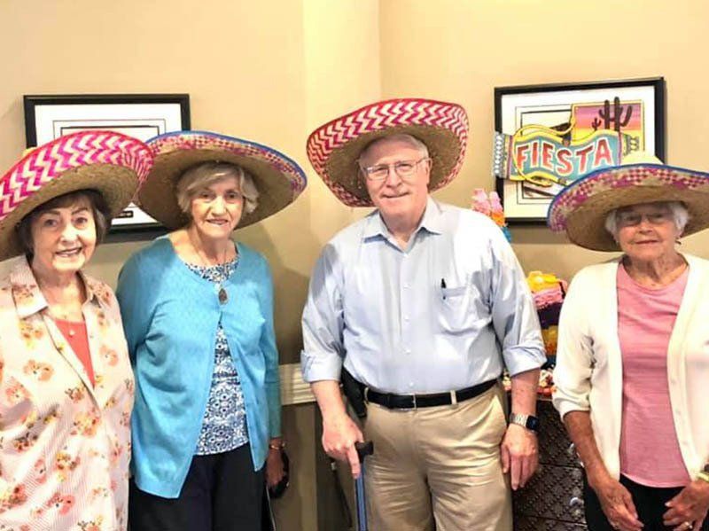 Four people wearing sombreros smile for a photo at a 