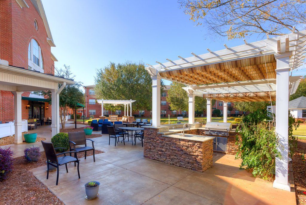 Outdoor patio with seating, pergola, and brick barbecue area on a sunny day.