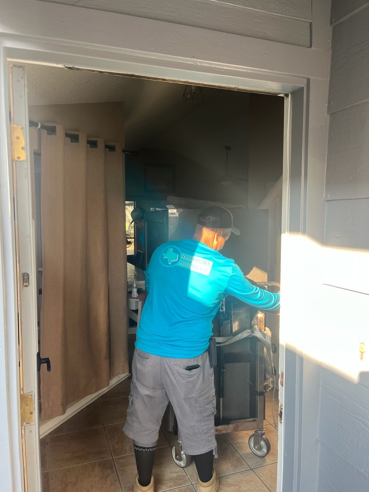 Man in blue shirt pushing cart through doorway.