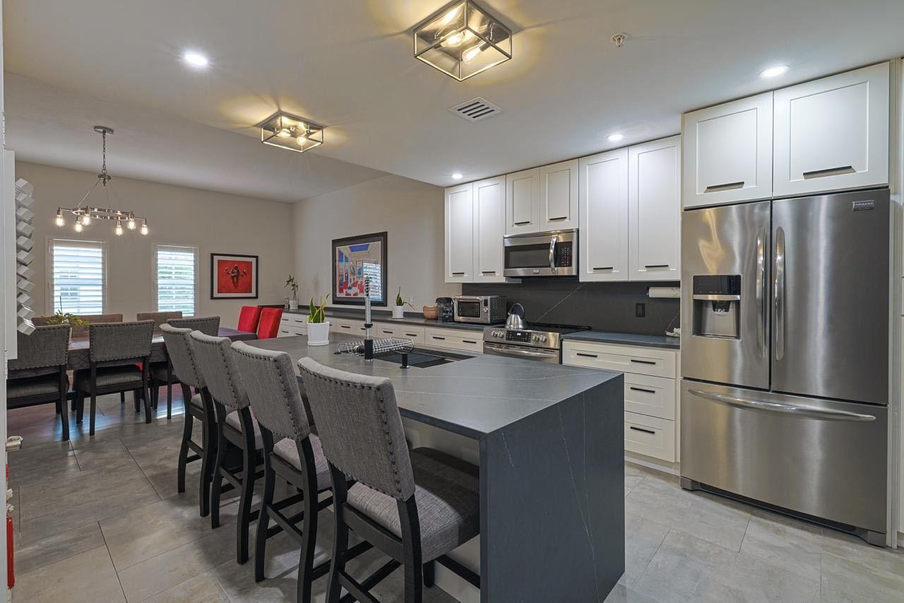 Modern kitchen with island seating, stainless steel appliances, and a dining area.