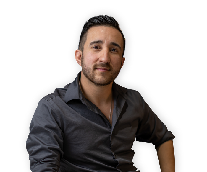Man with dark hair and a goatee, wearing a grey button-up shirt, smiles at the camera.