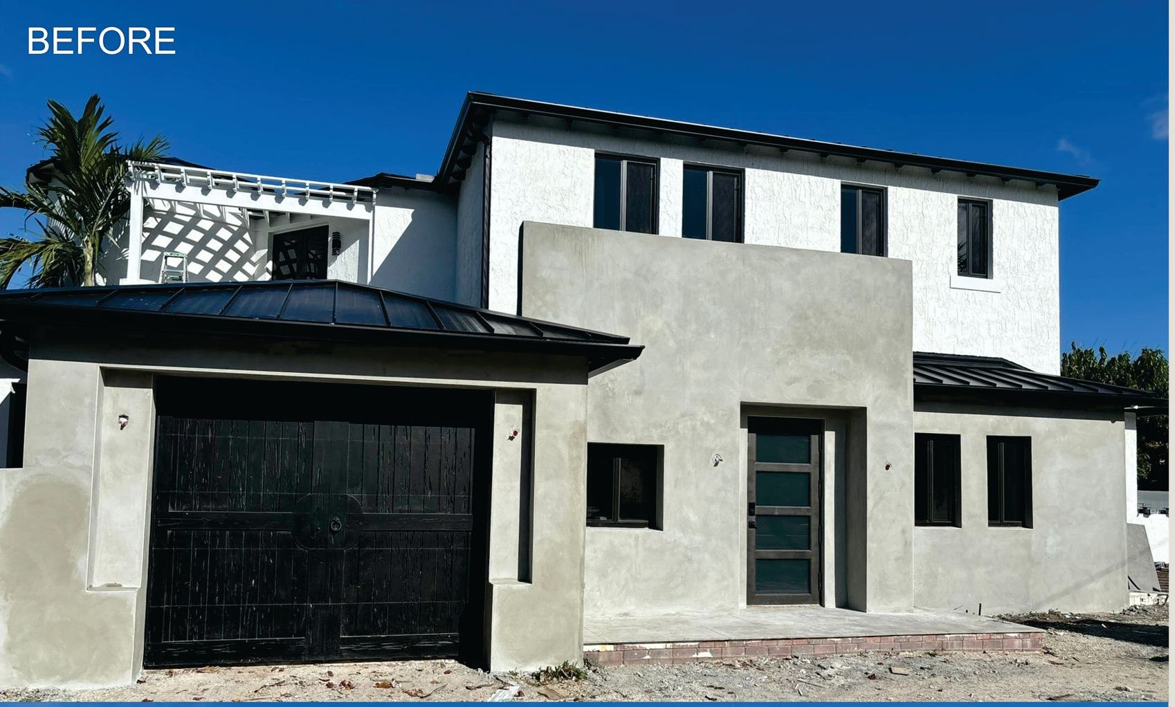 A before picture of a house with a black garage door