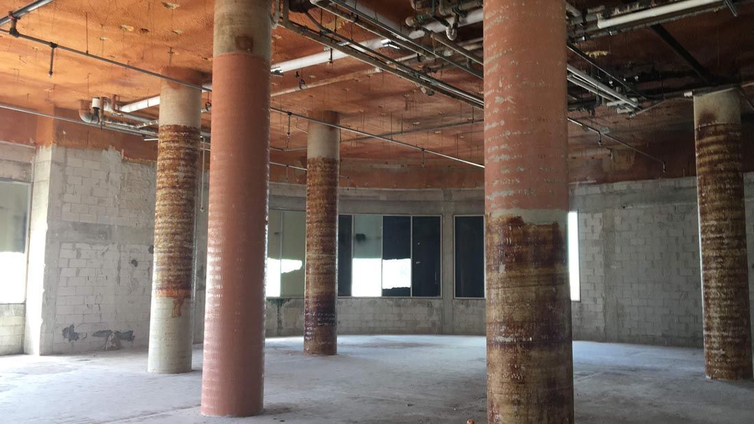 A large empty room with columns and pipes hanging from the ceiling.