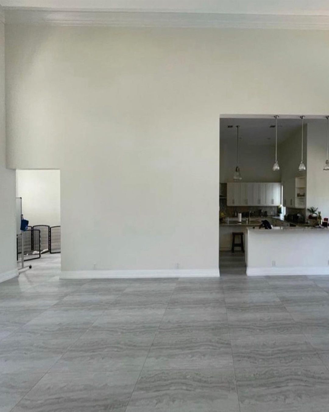 A large empty room with a kitchen in the background.