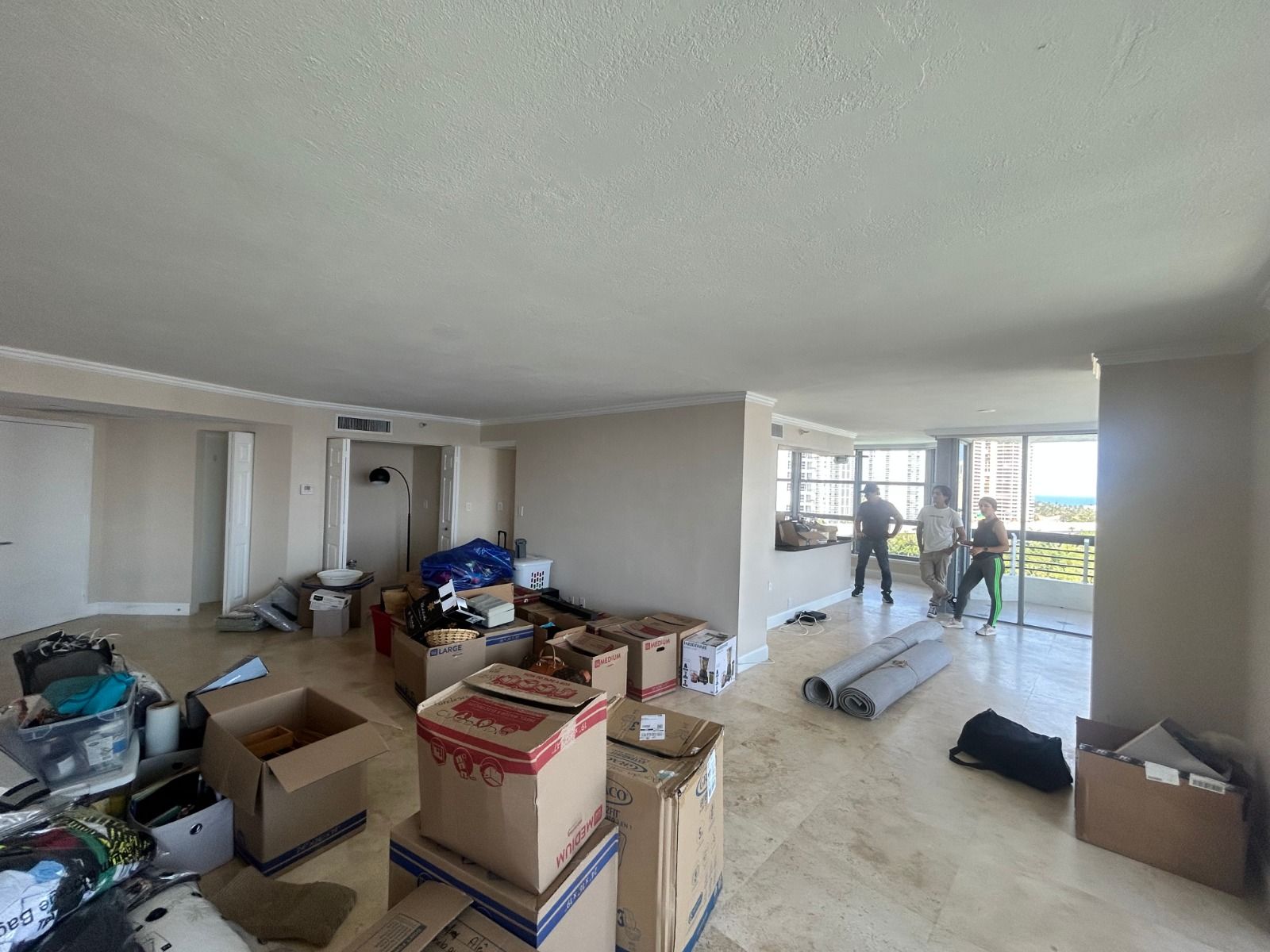 A living room filled with boxes and a man standing in the background.