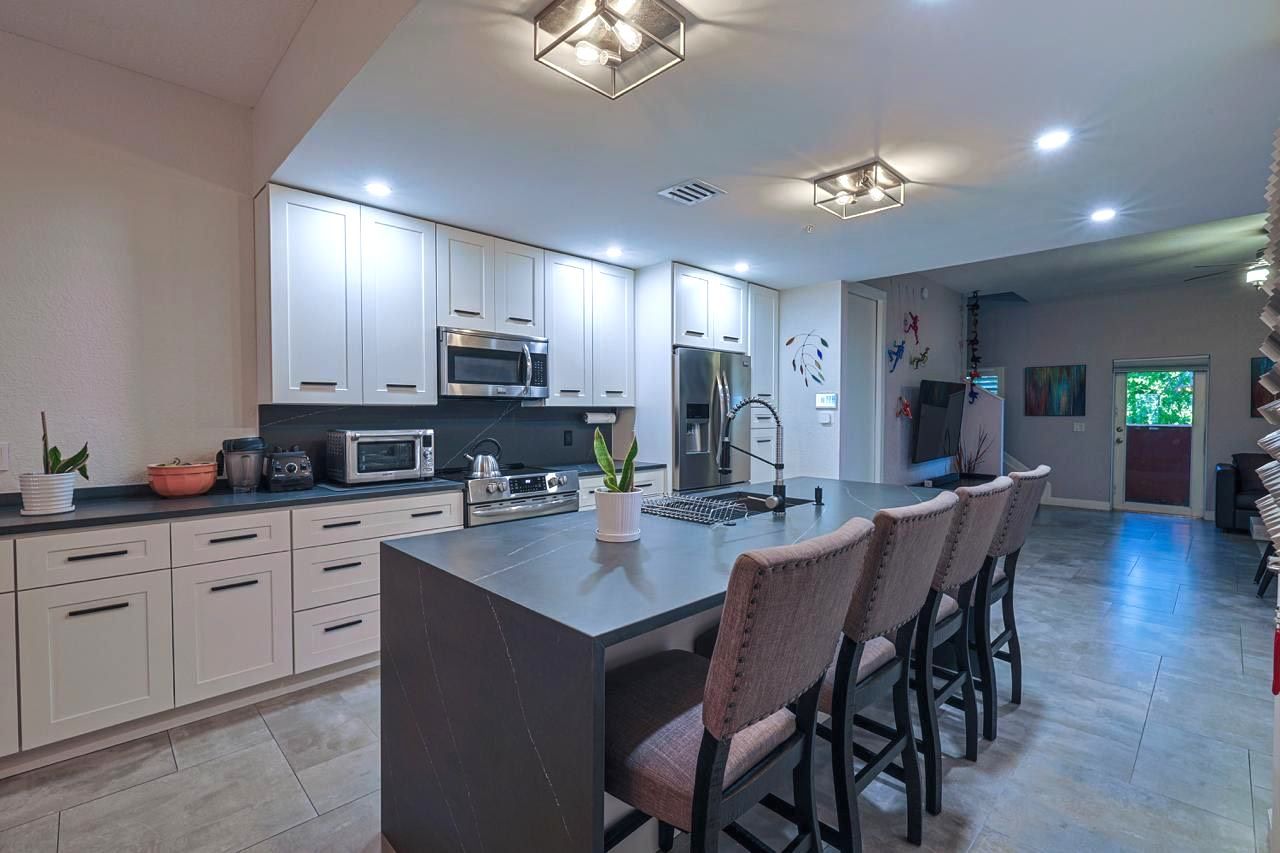 A kitchen with white cabinets , stainless steel appliances , and a large island.