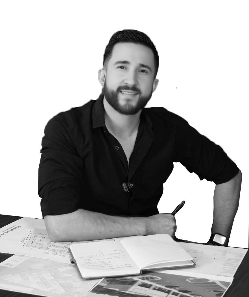 Man with dark hair and a goatee, wearing a grey button-up shirt, smiles at the camera.