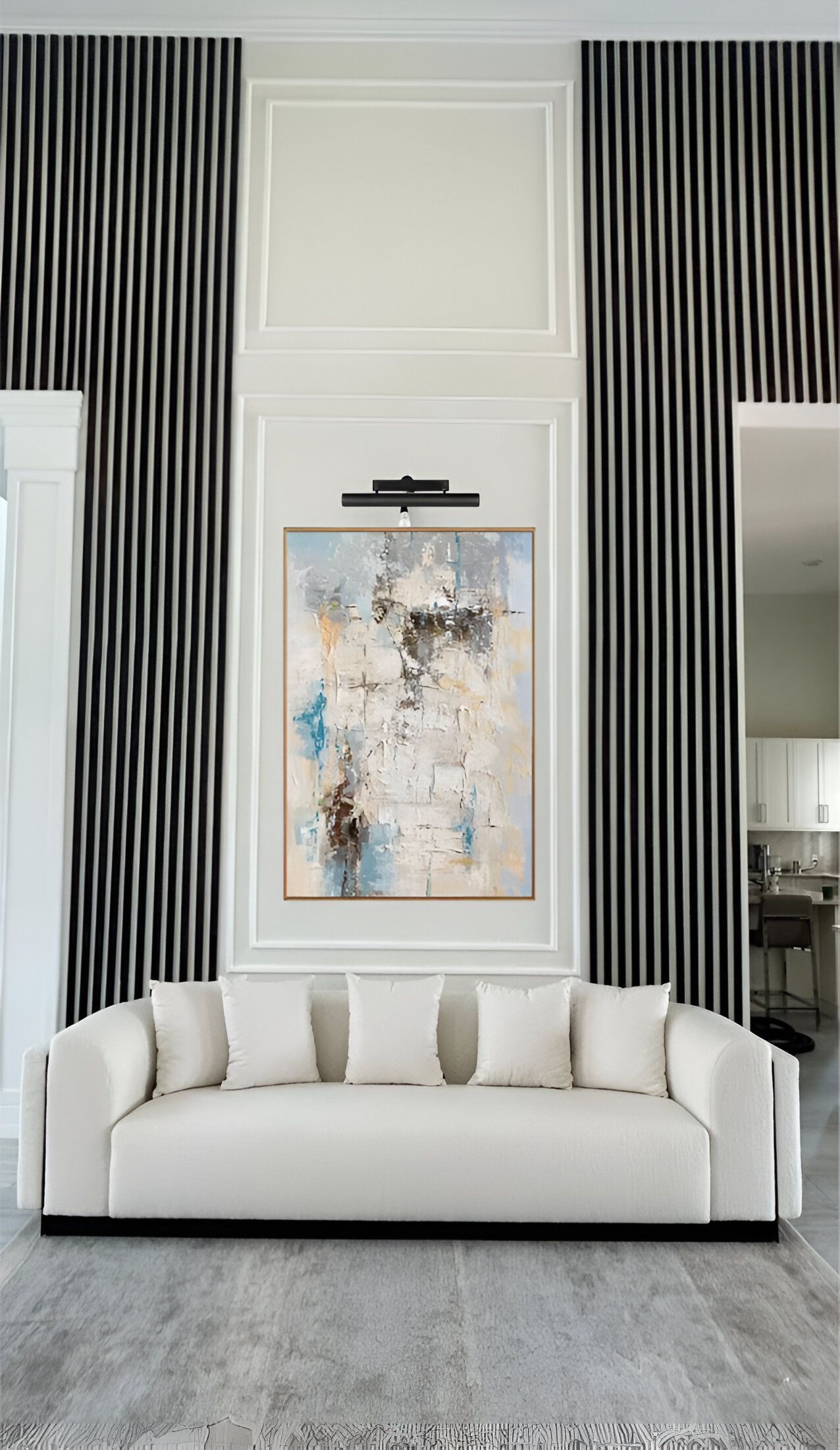 A living room with a white couch and a painting on the wall.