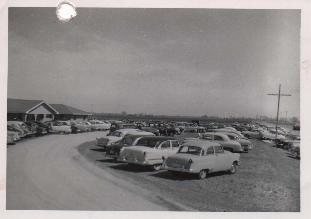 A black and white photo of cars parked in a parking lot