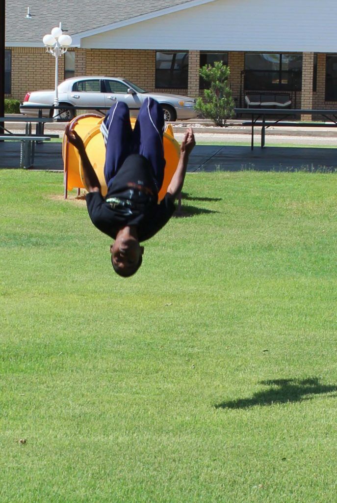 A man is doing a handstand in the air in a park.