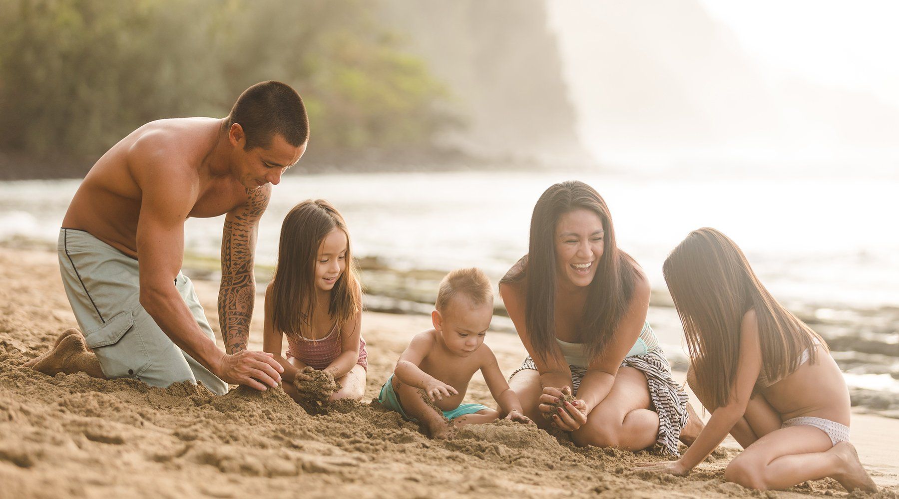A Hawaii family plays on a sandy beach together