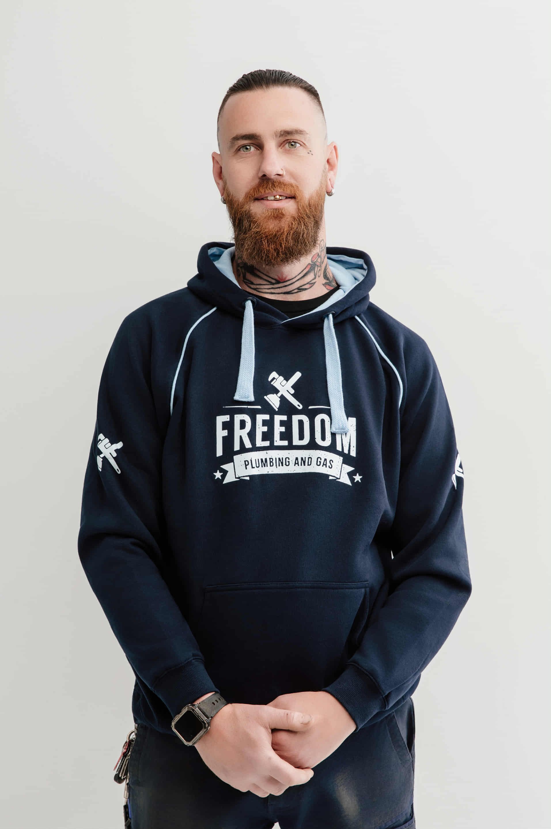 Man in navy hoodie with "FREEDOM PLUMBING AND GAS" and logo