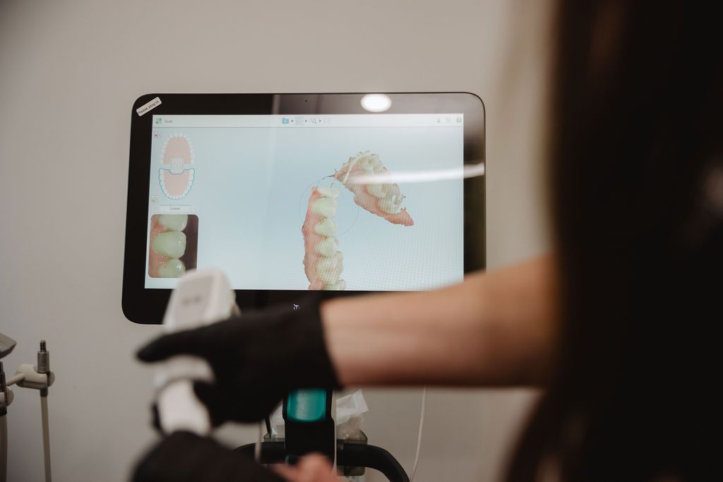 Dentist using scanner on patient, showing 3D teeth image on monitor.
