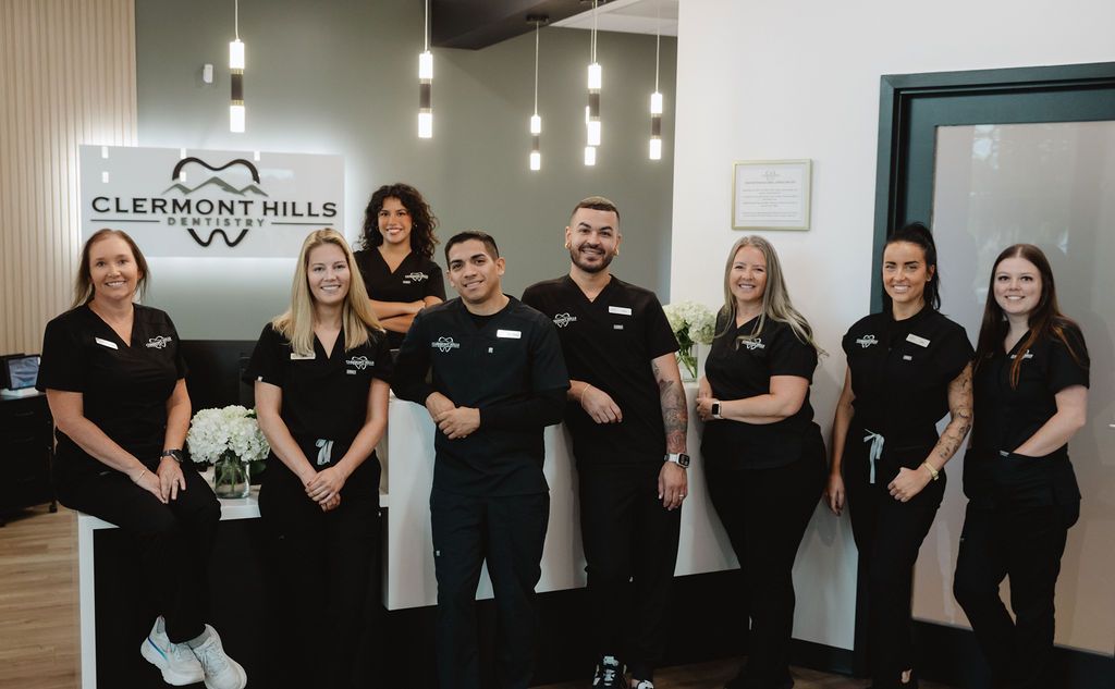 Group of dental staff posing in their office near the reception desk.