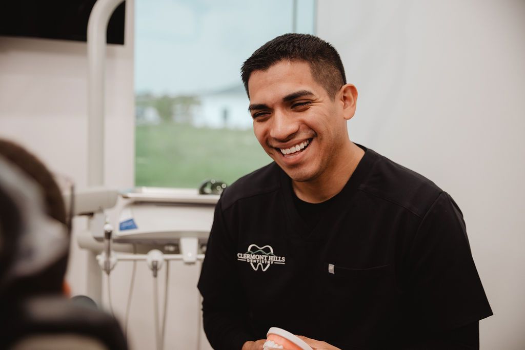 Dentist smiles while talking to a patient in a dental office.