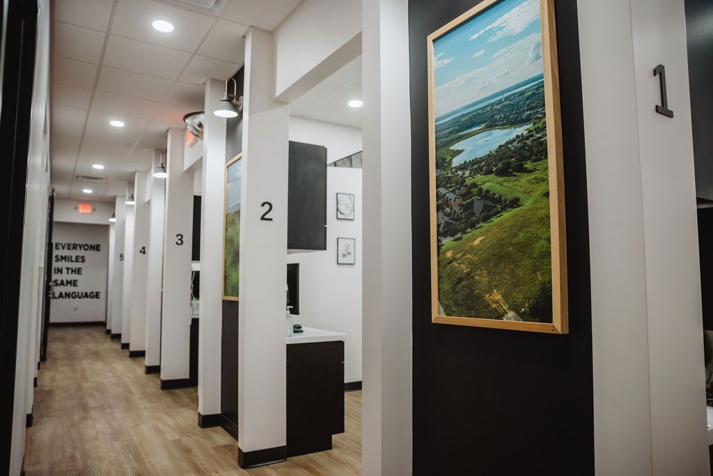 Hallway with numbered pillars and landscape art. Cubicles line the right, with a dark wall on the right and a light floor.
