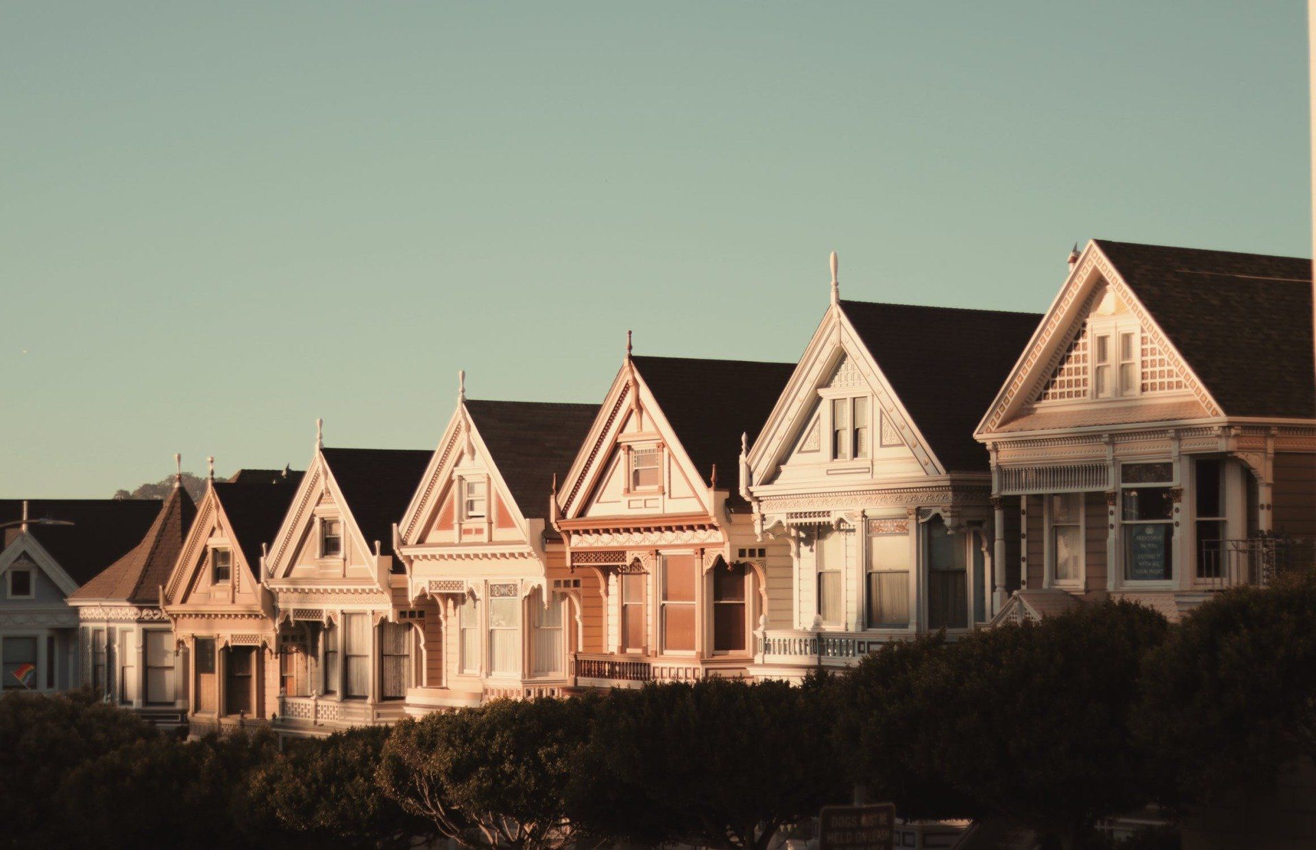 Row of colorful Victorian houses with gabled roofs under a clear sky.