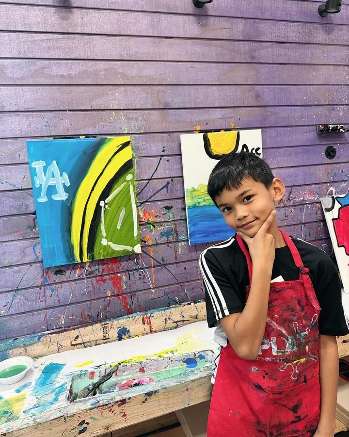 kid posing in front of paintings 