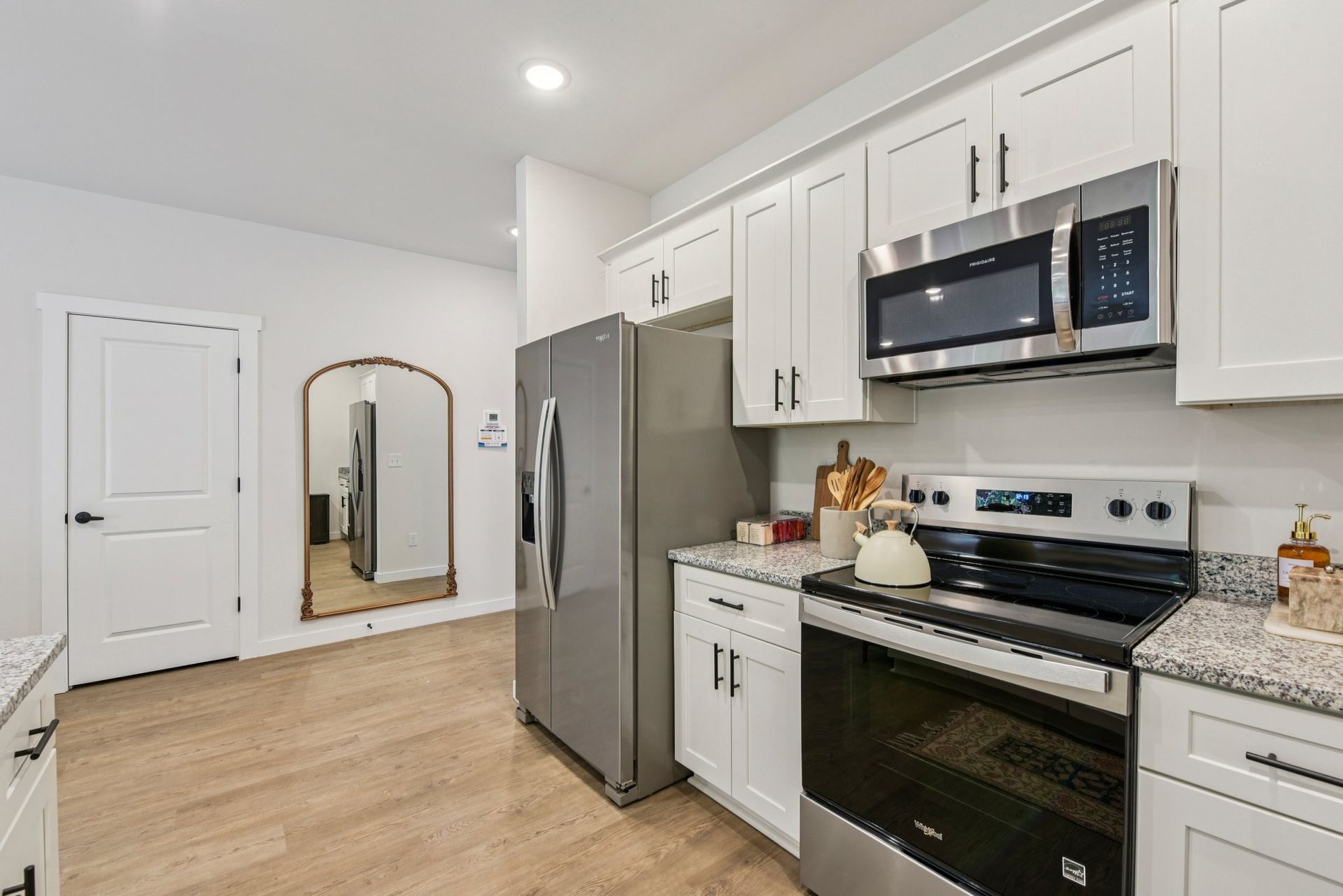 Kitchen with white cabinets, stainless steel appliances, and wood flooring.
