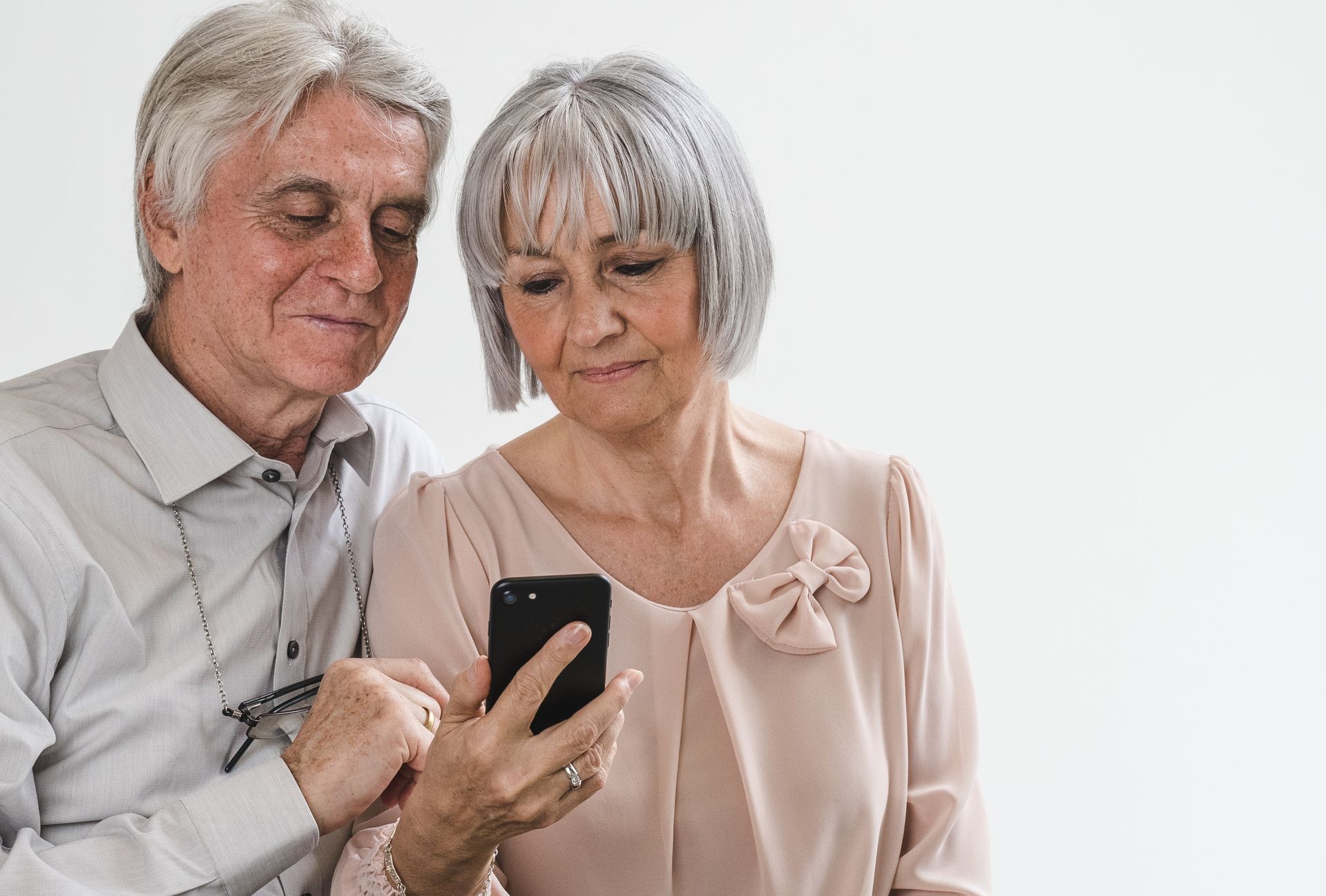 An elderly couple is using a remote heart health monitoring app on their smartphone