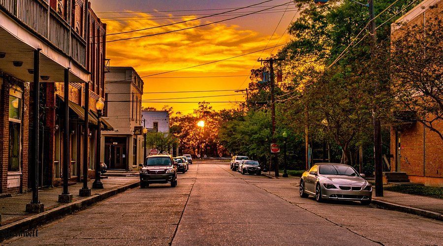 Street lined with buildings and cars at sunset; golden sky. New Orleans
