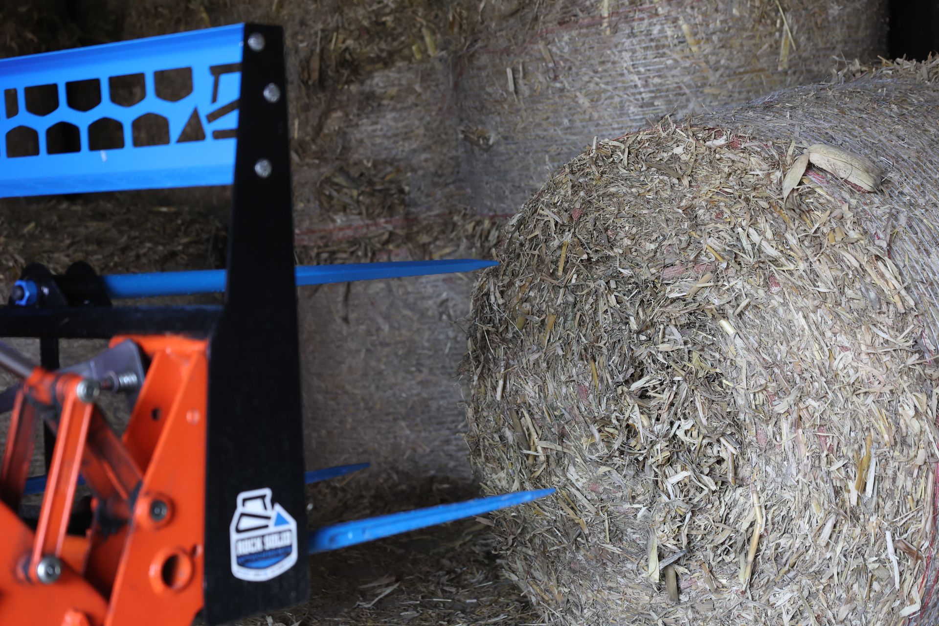 A bale of hay is being picked up by a machine