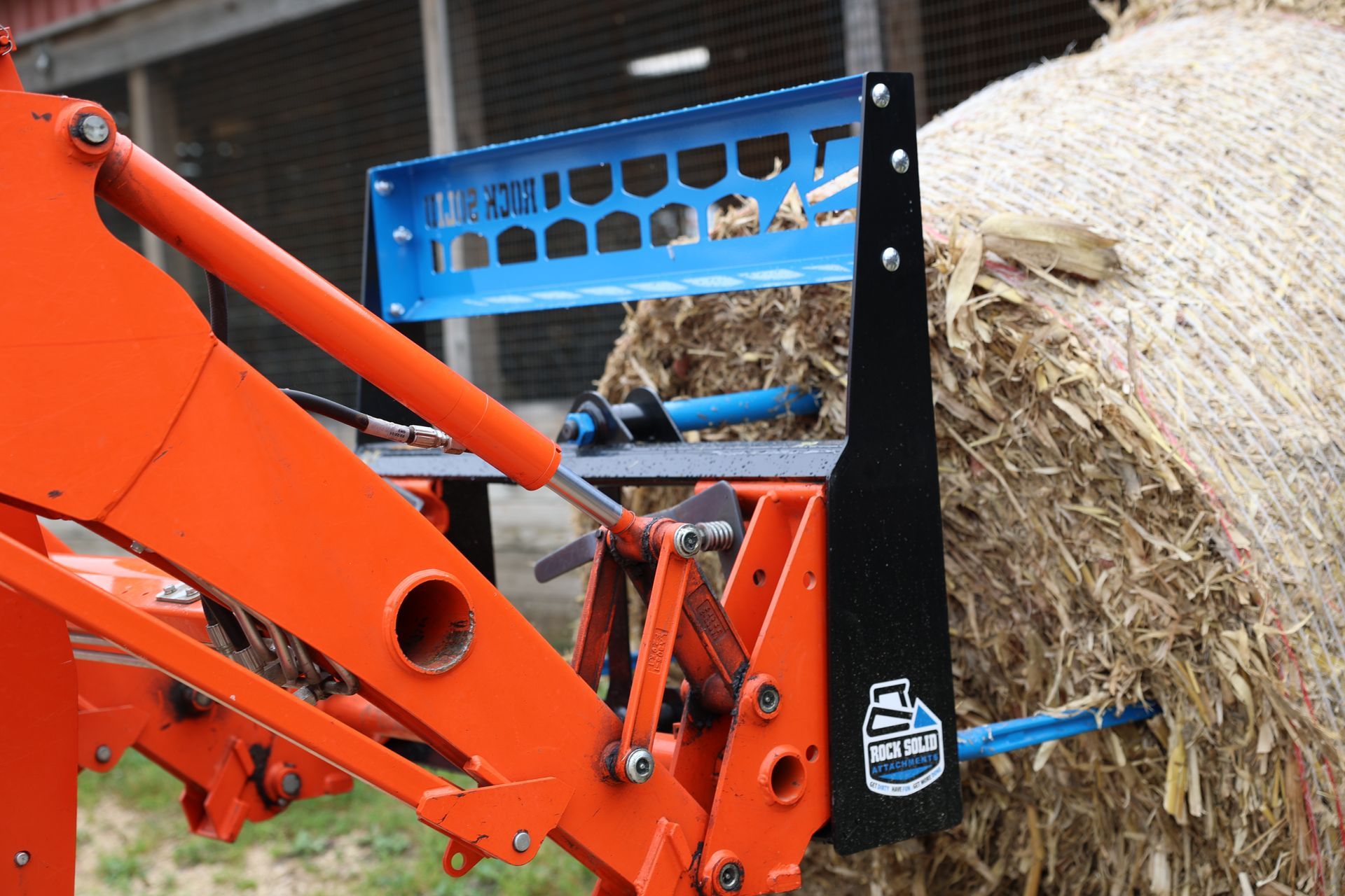 A tractor with a bale of hay attached to it.