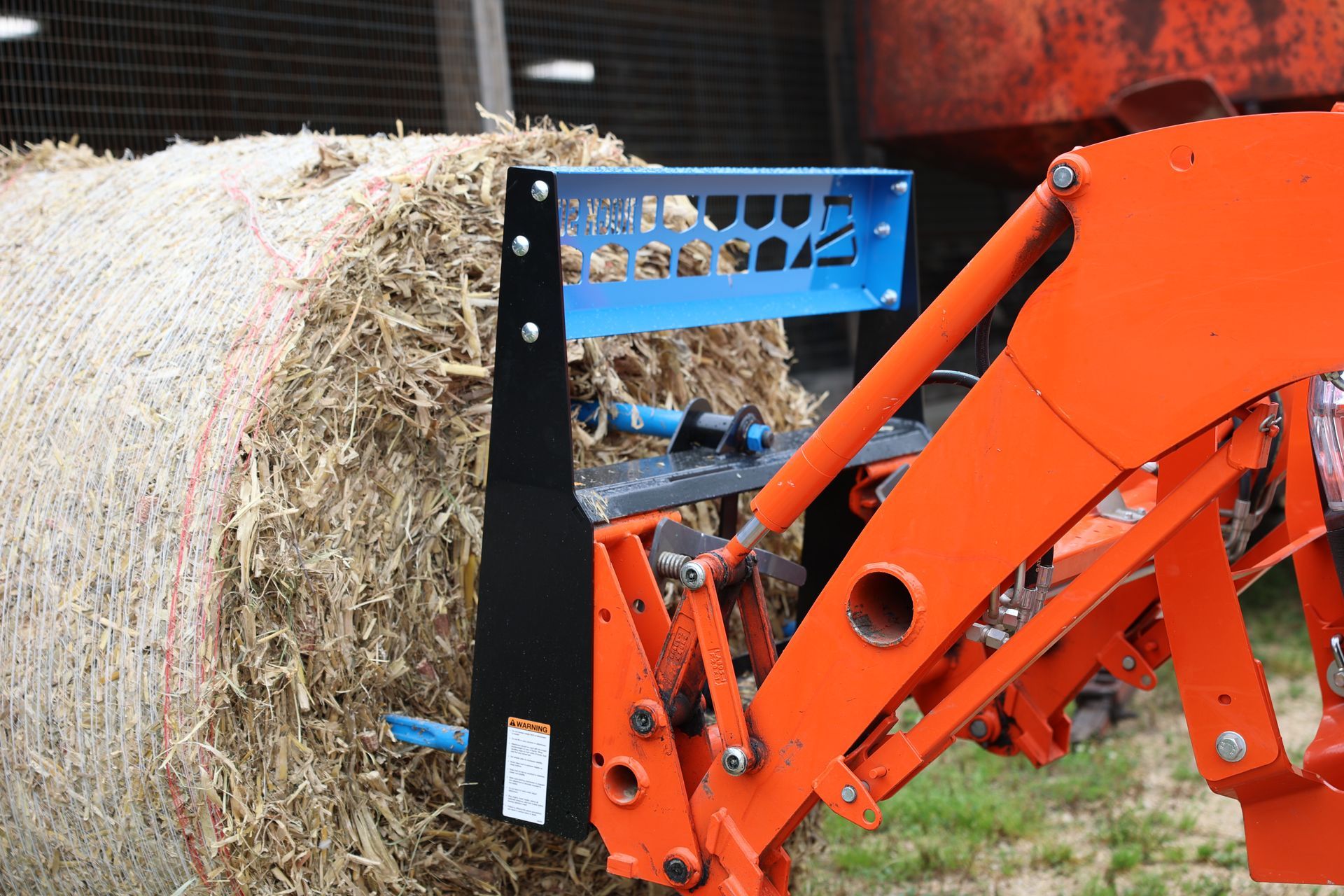 A large bale of hay is being lifted by a tractor.