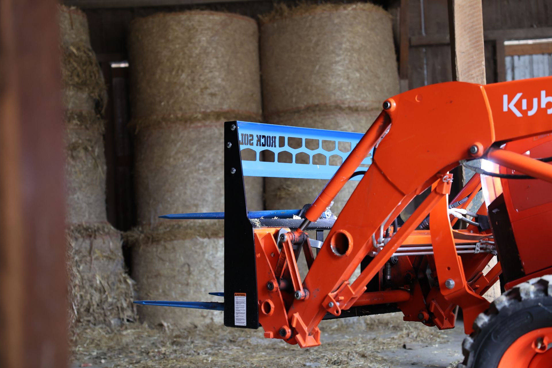 A kubota tractor is parked in front of bales of hay