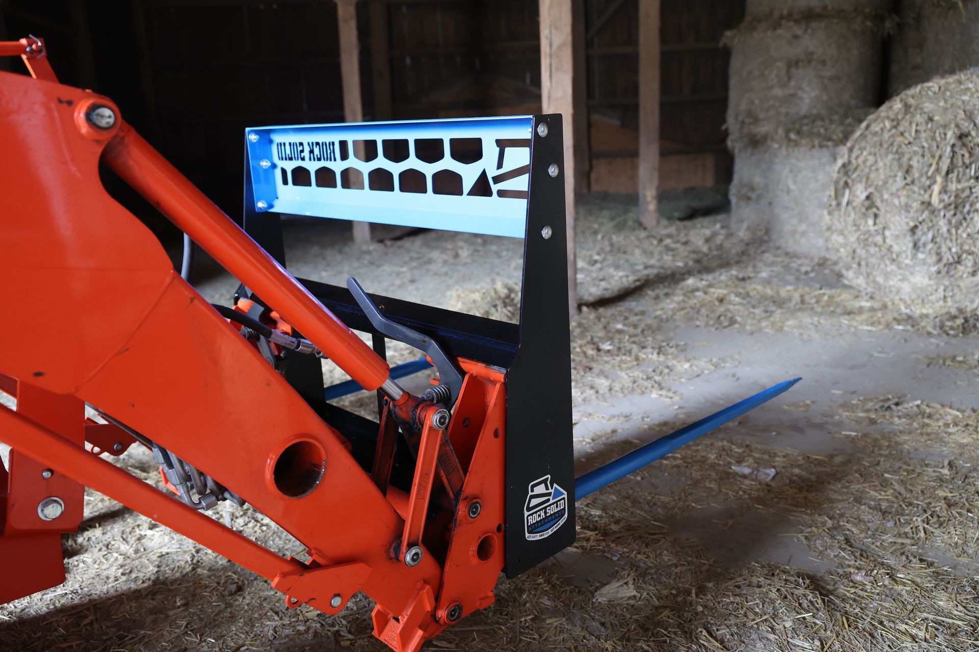 A tractor with a fork attached to it in a barn