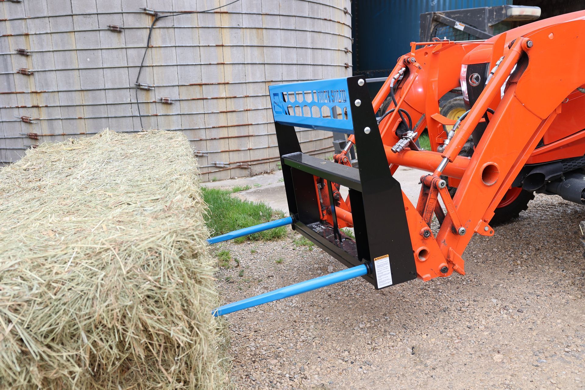 A large bale of hay is being loaded onto a tractor.