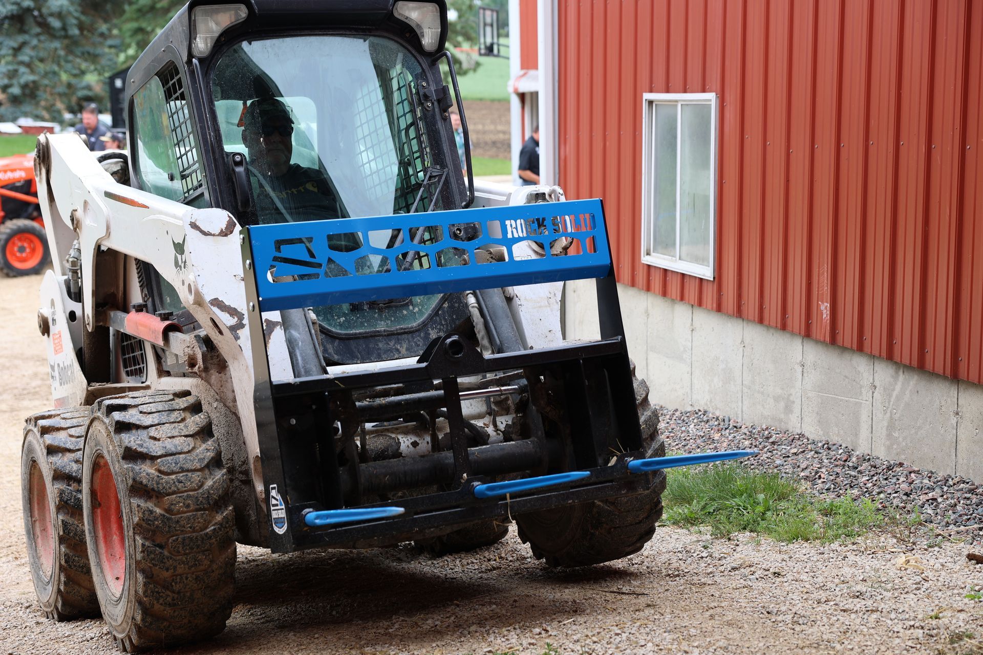 A bobcat is parked in front of a red building