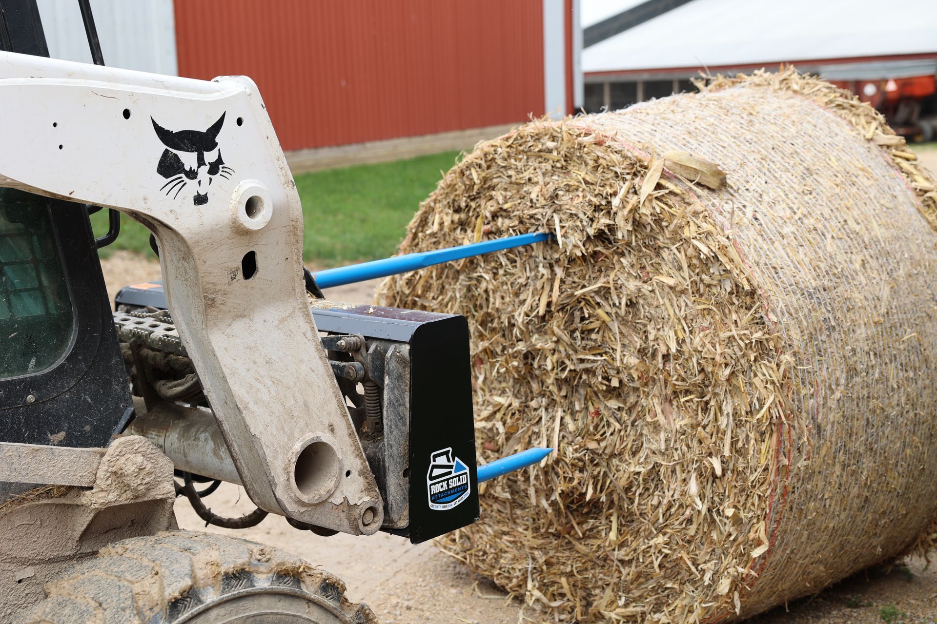 A tractor is carrying a large bale of hay.