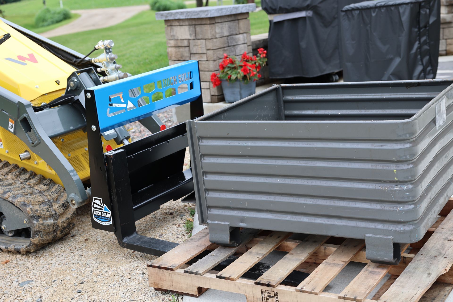 A forklift is sitting on a wooden pallet next to a metal box.
