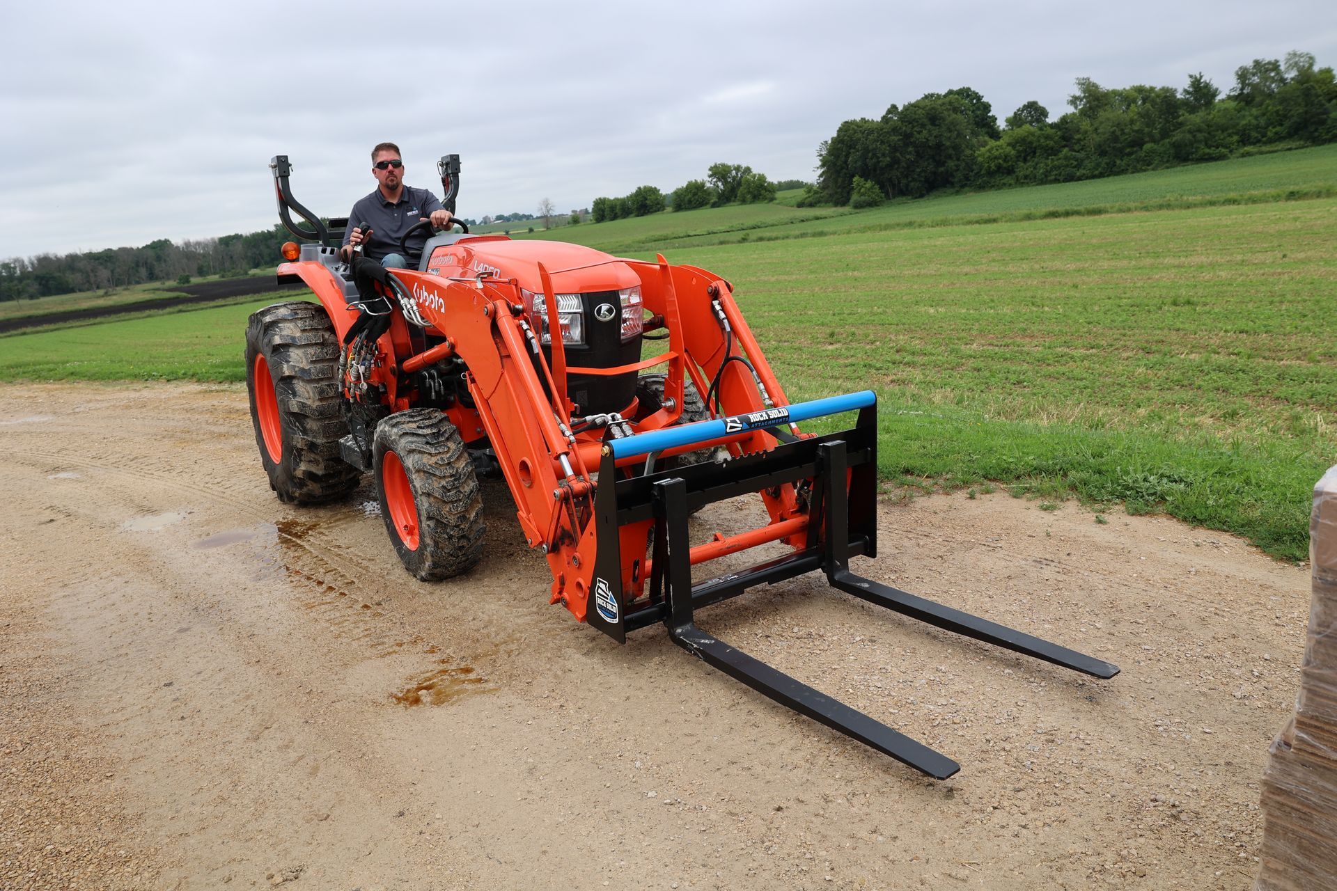 A man is driving a tractor with a forklift attached to it.