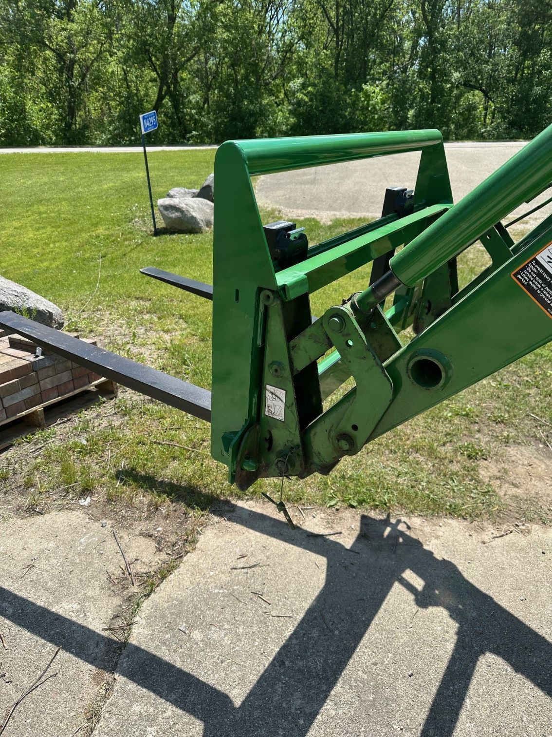 A green forklift is parked on the side of the road.