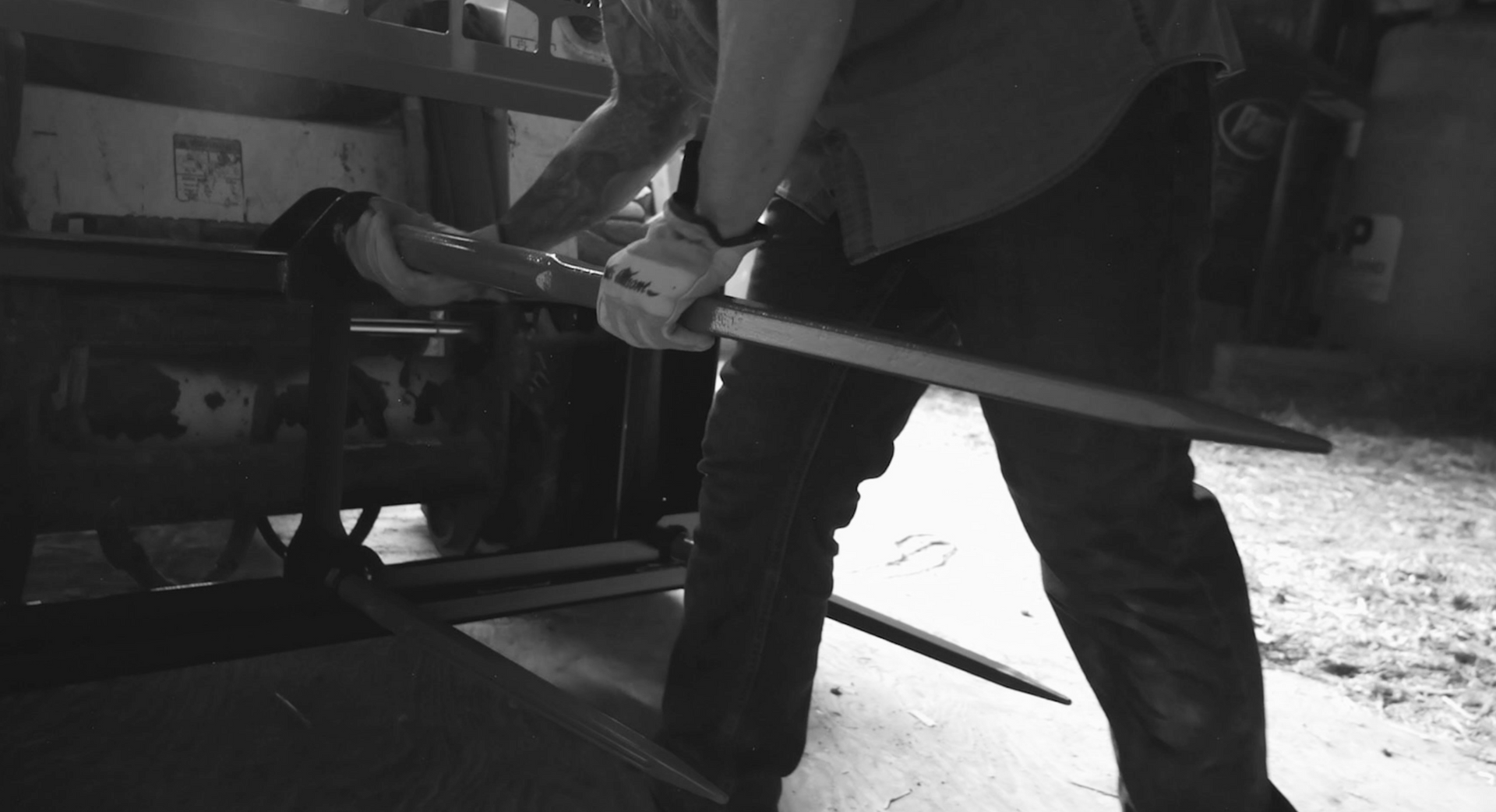 A black and white photo of a man holding a large stick.